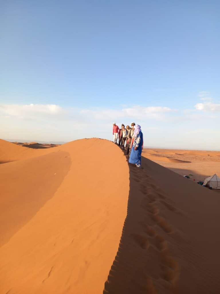 Le groupe admire le panorama sur l'erg Chegaga depuis le sommet d'une grande dune.